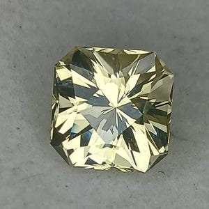 May include: A light yellow gemstone with a square shape and a faceted cut.