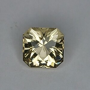 May include: A light yellow, faceted gemstone with a square shape.