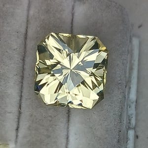 May include: A square-shaped, faceted, yellow gemstone with a star-like pattern in the centre.