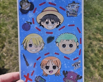May include: A blue postcard featuring cartoon illustrations of characters from the anime series One Piece. The card includes images of Luffy, Zoro, Nami, Sanji, Chopper, and other elements like a ship and a map.