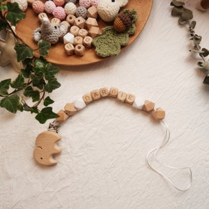 Peut inclure: Un hochet en bois pour b&eacute;b&eacute; avec le nom "DARCIE" &eacute;crit en perles de bois. Le hochet est muni d'une attache en bois en forme d'&eacute;l&eacute;phant.