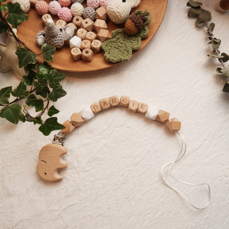 Peut inclure: Un hochet en bois pour b&eacute;b&eacute; avec le nom "DARCIE" &eacute;crit en perles de bois. Le hochet est muni d'une attache en bois en forme d'&eacute;l&eacute;phant.