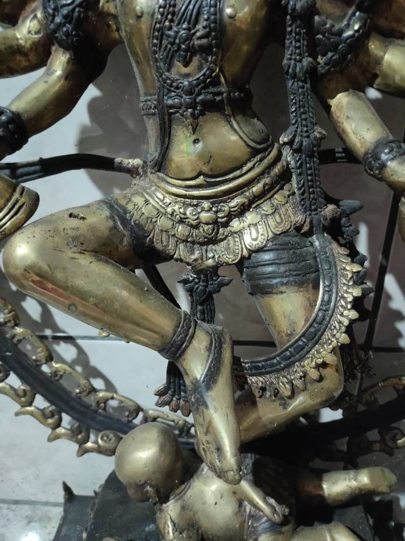Op de afbeelding: Een gouden beeld van een hindoe&iuml;stische godheid met meerdere armen, dansend op een kleiner figuur. Het beeld is ingewikkeld versierd met sieraden en kleding.