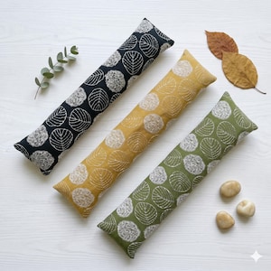 May include: A white ceramic mug with a black handle and the text "But First, Coffee" in a bold, black font. The mug is set against a blurred background, suggesting a cozy setting.