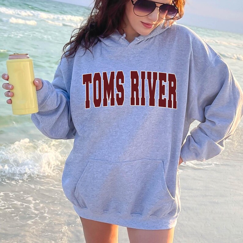 May include: A gray hoodie with a maroon "TOMS RIVER" graphic on the front. The hoodie has a drawstring hood and a kangaroo pocket.