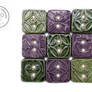Peut inclure: Neuf boutons en céramique disposés en grille carrée. Les boutons sont carrés et ont un design à deux trous. Les boutons sont verts et violets avec des motifs complexes.