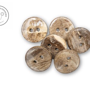 Peut inclure: Six boutons en céramique de différentes nuances de brun et de blanc avec un motif moucheté. Les boutons ont deux trous chacun.