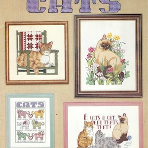Puede incluir: Un libro de patrones de punto de cruz titulado "CATS" con diseños de gatos enmarcados. Los diseños incluyen un gato en una silla, un gato siamés en flores y varias ilustraciones de gatos con texto. El libro es de la American School of Needlework.