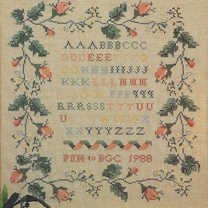 以下が含まれることがあります： さまざまな色のアルファベットが刺繍されたクロスステッチのサンプラー。緑の葉、赤いベリー、小さな白い花で縁取られています。「PIN to BGC 1988」の文字が下部に刺繍されています。背景はベージュ色の生地です。