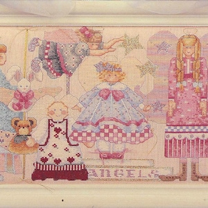 Puede incluir: Imagen enmarcada en blanco de un bordado a punto de cruz que representa ángeles y niños. Los ángeles visten vestidos y delantales, con halos y alas. La palabra « ANGELS » está bordada en la parte inferior. Paleta de colores rosa, azul y blanco.