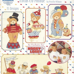 Peut inclure: Un livre de patrons de point de croix intitulé "Cherished Teddies Circus On Parade" par Priscilla Hillman. La couverture présente des ours en peluche en costumes de cirque, avec le texte "15 Designs" et la marque "Hobby Lobby".