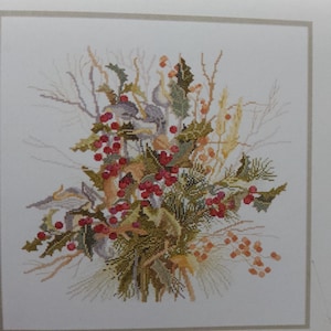 May include: Cross-stitch artwork of a floral arrangement. The design features red berries, green leaves, and various other plant elements in shades of brown, yellow, and green. The artwork is framed.