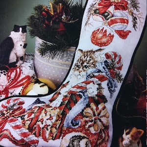 May include: A Christmas stocking with a cross-stitch design featuring a kitten, Christmas ornaments, and wrapped gifts. The name "JASON" is stitched at the top. The words "Christmas Surprise Stocking" are at the top.