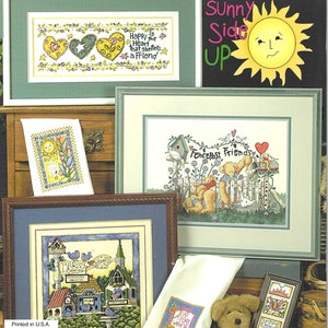 Könnte beinhalten: Eine Sammlung gerahmter Kreuzstichmuster mit verschiedenen Designs. Die Muster umfassen Blumenmotive, Herzen und Szenen mit Vögeln und Bären. Der Text "Sunny Side Up" ist sichtbar, zusammen mit dem Text "Happy is the heart that shelters a friend."