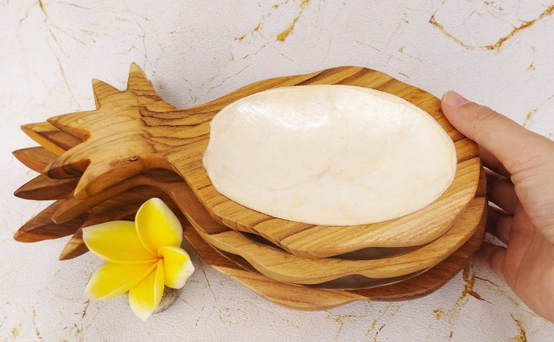 May include: Three wooden pineapple-shaped serving dishes with a white mother-of-pearl bowl insert. The dishes are stacked on top of each other.