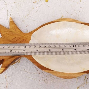 May include: A wooden pineapple-shaped dish with a white mother-of-pearl interior. The dish measures approximately 9 inches long.