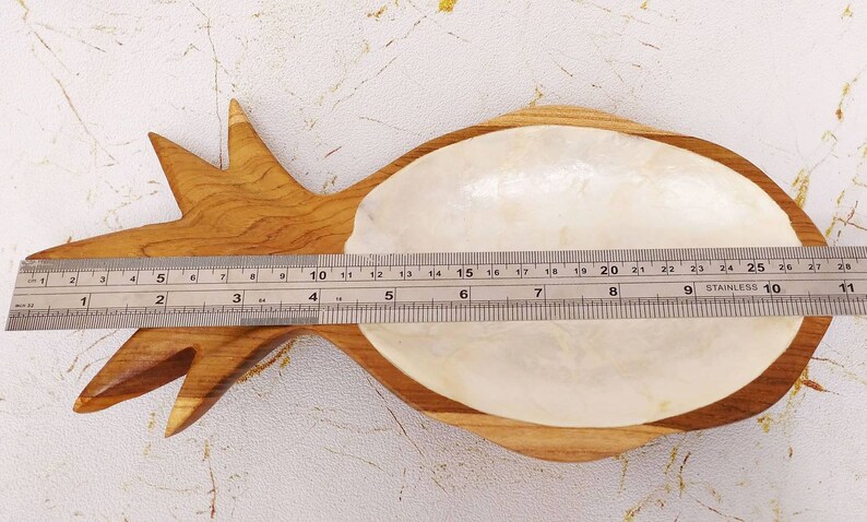 May include: A wooden pineapple-shaped dish with a white mother-of-pearl interior. The dish measures approximately 9 inches long.