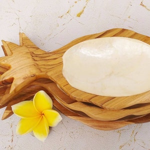 May include: A wooden pineapple shaped serving bowl with a white mother of pearl insert. The bowl is made of natural wood and has a rustic look.