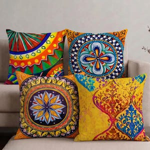 May include: Four square throw pillows featuring vibrant, multi-colored patterns. One displays a radial geometric design, another a central blue and orange floral medallion, a third a yellow and purple mandala, and the fourth a yellow damask print.