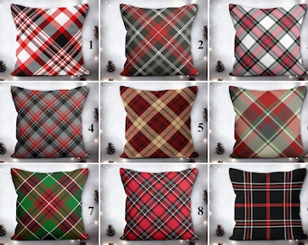 May include: Nine square cushions featuring diverse tartan patterns in red, black, white, and green. The cushions are displayed against a light backdrop with pine cones. The plaid designs consist of diagonal and intersecting lines, offering a traditional, decorative aesthetic.