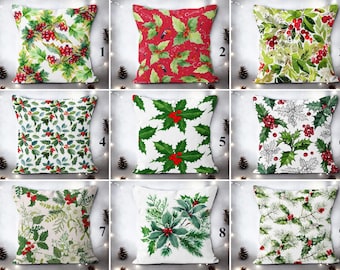 May include: Nine decorative throw pillows with Christmas-themed designs. The pillows feature various patterns of green holly leaves and red berries on white, red, and green backgrounds. The pillows are square and suitable for home decor.