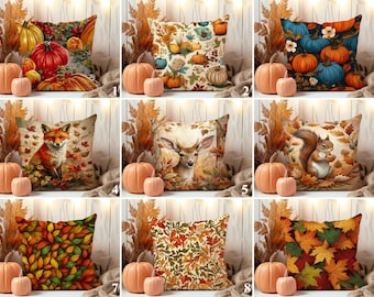 May include: A collection of decorative throw pillows with autumn-themed designs. Pillows feature images of pumpkins, leaves, foxes, deer, and squirrels. The pillows are surrounded by pumpkins and fall foliage, creating a seasonal display.