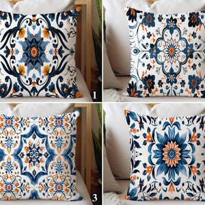 Può includere: Quattro cuscini decorativi con intricati motivi floreali. Ogni cuscino presenta uno sfondo bianco con disegni blu e arancioni. I motivi includono fiori stilizzati, foglie e forme geometriche.