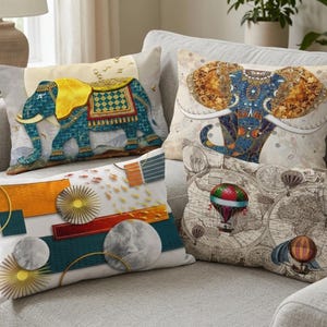 May include: Four decorative throw pillows on a gray sofa. Pillows feature colorful designs including an elephant, an abstract geometric pattern, and hot air balloons over a vintage map. The pillows add a decorative touch to the living room.