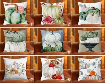 Könnte beinhalten: Dekorative Kissen mit Aquarell-Kürbis-Designs. Kissen zeigen verschiedene Kürbisarrangements in Grün-, Weiß- und Orangetönen mit floralen und Blatt-Akzenten. Perfekt für die Herbstdekoration.