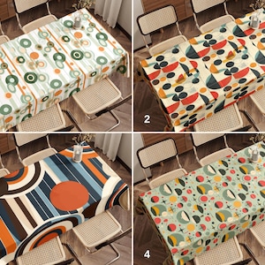 May include: Four different tablecloths featuring geometric patterns in shades of green, orange, blue, and red. The tablecloths are displayed on tables with wicker chairs.