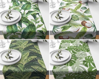 Puede incluir: Cuatro caminos de mesa diferentes con patrones de hojas tropicales. Los caminos de mesa son blancos con hojas verdes y presentan diferentes diseños. El primer camino de mesa tiene hojas verdes grandes, el segundo tiene hojas más pequeñas y cocos, el tercero tiene un fondo verde oscuro con hojas grandes y el cuarto tiene grandes hojas de monstera verdes.