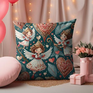 Peut inclure: Coussin carré décoratif avec un fond bleu-vert représentant des illustrations de chérubins avec des ailes blanches, des cœurs et des motifs ornés en rouge et marron. Le coussin est de forme carrée.