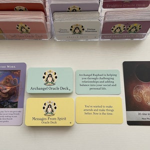 Op de afbeelding: Vijf orakelkaarten met kleurrijke achtergronden en illustraties. De kaarten zijn getiteld "Do the Work", "Archangel Oracle Deck", "Messages From Spirit Oracle Deck", "Archangel Raphael is helping you through challenging relationships and adding balance into your social and personal life." en "It's time to take action New Moon in Aries".