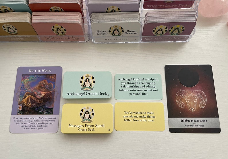 Op de afbeelding: Vijf orakelkaarten met kleurrijke achtergronden en illustraties. De kaarten zijn getiteld "Do the Work", "Archangel Oracle Deck", "Messages From Spirit Oracle Deck", "Archangel Raphael is helping you through challenging relationships and adding balance into your social and personal life." en "It's time to take action New Moon in Aries".