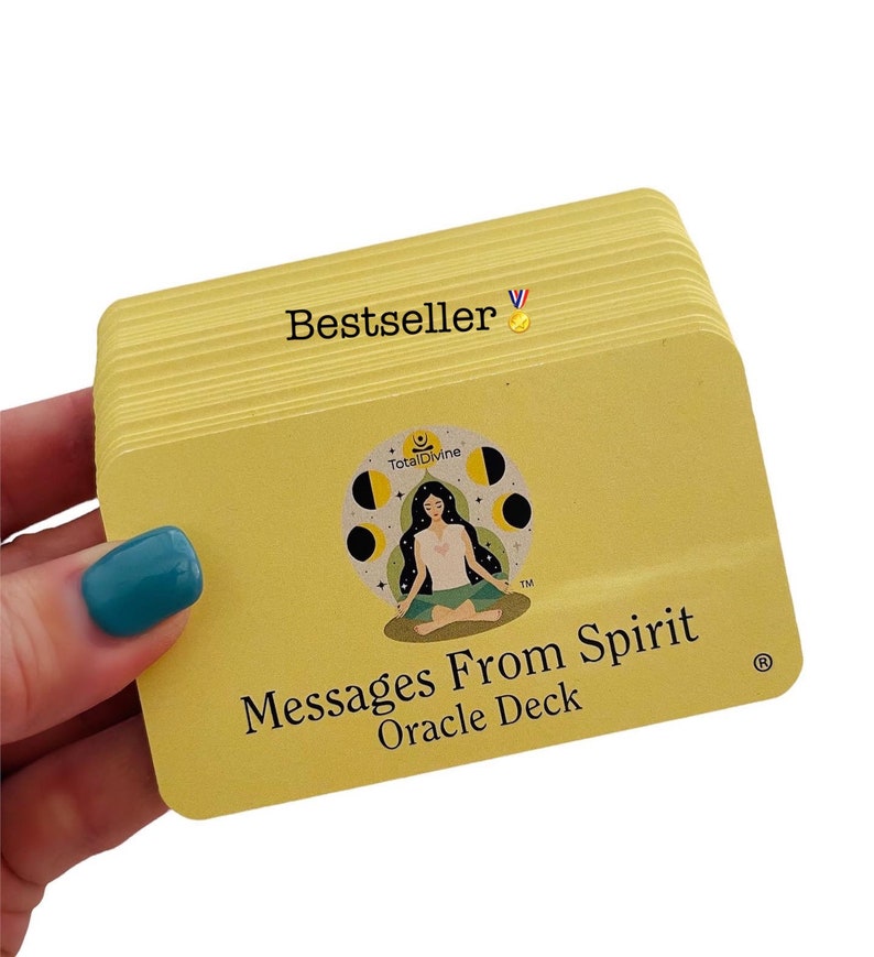 Op de afbeelding: Een stapel gele orakelkaarten met de tekst "Bestseller" en een gouden medaille-icoon. De voorkant van de kaarten toont een mediterende vrouw met een maan- en sterrenontwerp. De tekst "Messages From Spirit Oracle Deck" is op de kaarten gedrukt.