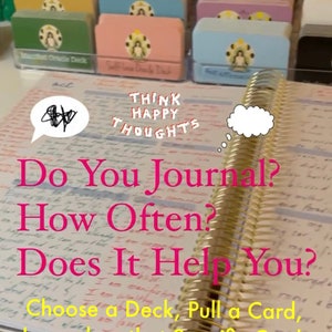 May include: A close-up of an open journal with the text "Do You Journal? How Often? Does It Help You? Choose a Deck, Pull a Card, Journal on that Specific Card." written in pink. The journal has gold rings and is lying on a table with a stack of colorful card decks in the background. The text "Think Happy Thoughts" is written in white on a pink card deck. A sticker with the text "Positive thought" is in the foreground.
