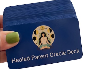 Pode incluir: Um baralho de cartas azul com o texto "Healed Parent Oracle Deck" e um logotipo que diz "TotalDivine" com uma mulher meditando em um círculo de luas.