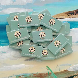 May include: A stack of teal blue cards with the text "Co-Dependent Oracle Deck" printed on each card. The cards feature a stylized illustration of a person sitting in a meditative pose.