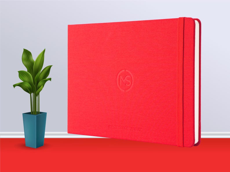 May include: A red hardback notebook with a white elastic band closure and a small embossed logo on the front. The notebook is on a red surface.