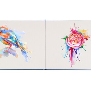 May include: A watercolor painting of a bluebird with orange accents perched on a rock with colorful water splatter. The second page of the book features a watercolor painting of a pink rose with colorful water splatter.