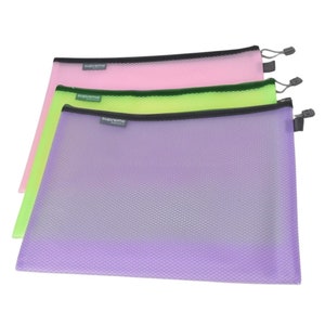 May include: Three mesh zipper pouches in pink, green, and purple. Each pouch has a black zipper and a small gray label with the word "supreme" printed on it. The pouches are designed for organizing and storing items.