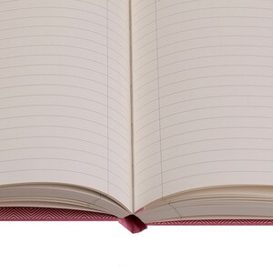 Pode incluir: Um caderno aberto com p&aacute;ginas pautadas e uma capa com padr&atilde;o chevron rosa.