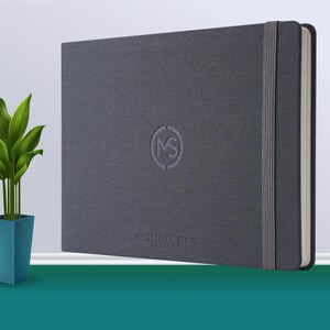 May include: A grey hardcover notebook with a grey elastic band closure and the text "WATERCOLOR ALBUM" printed on the front cover. The notebook has a circular logo with the letters "MS" inside.
