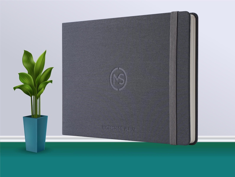 May include: A grey hardcover notebook with a grey elastic band closure and the text "WATERCOLOR ALBUM" printed on the front cover. The notebook has a circular logo with the letters "MS" inside.
