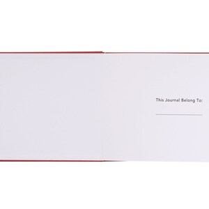 May include: A red journal with a blank page open to the inside cover. The inside cover has the text "This Journal Belong To:" printed on it.
