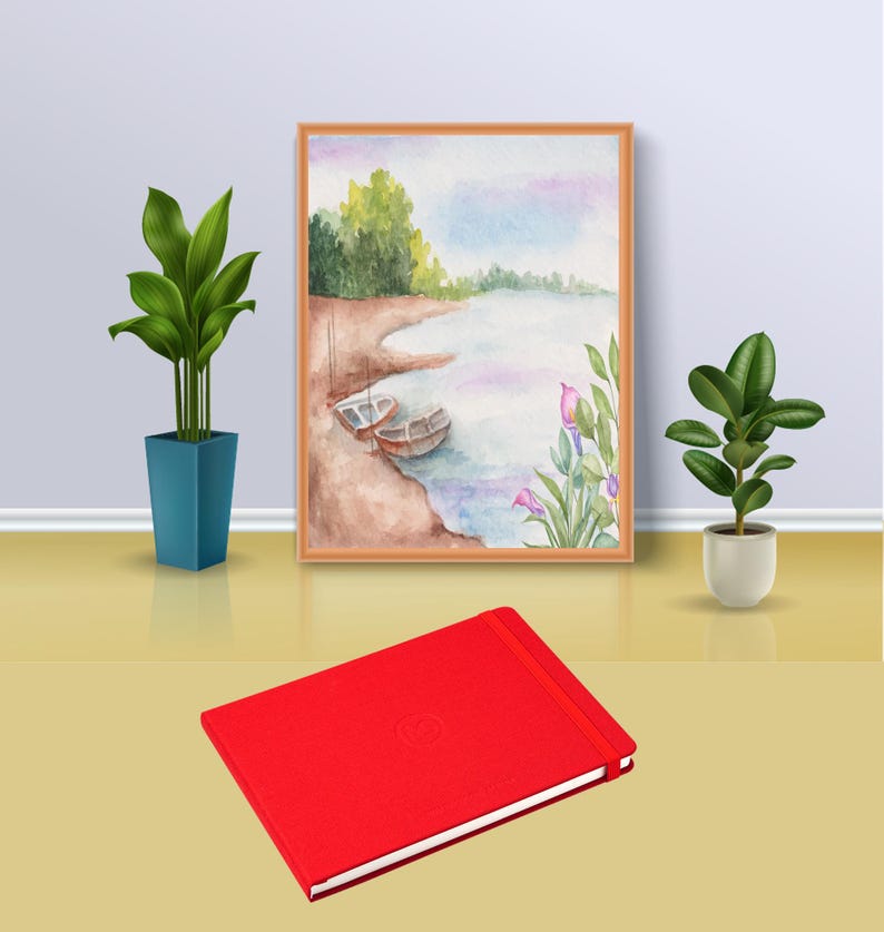 May include: A red hardback journal with a subtle embossed design. The journal is sitting on a light brown surface in front of a framed watercolour painting of a lake scene with boats and flowers.