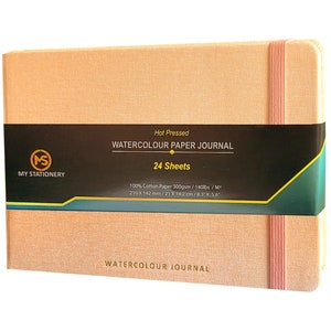 May include: A peach-coloured watercolour journal with a black and green label that reads "Hot Pressed Watercolor Paper Journal 24 Sheets 100% Cotton Paper 300gsm/140lbs/M² 210 x 142 mm/21 x 142 cm/8.3 x 5.6" and a pink elastic band.