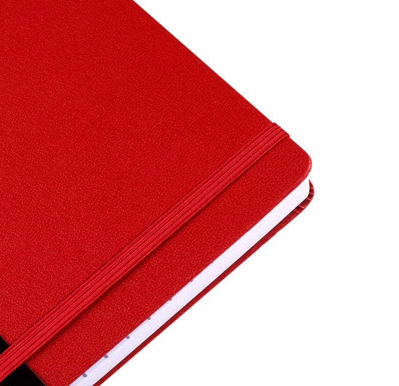 May include: A red notebook with a textured cover and a matching elastic band closure. The notebook's pages are white with a dotted pattern. The design is simple and classic.