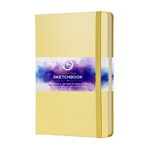 Puede incluir: Un cuaderno de bocetos amarillo con cierre de banda el&aacute;stica. La portada presenta una etiqueta con el texto "SKETCHBOOK" y detalles sobre el papel, incluido su tama&ntilde;o: 14,5 x 21 cm. El cuaderno tiene 120 p&aacute;ginas sin &aacute;cido.