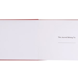 May include: A red journal with a blank page open to the inside cover. The inside cover has the text "This Journal Belong To:" printed on it.